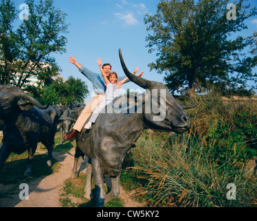 Mann mit seiner Tochter sitzt auf einer Kuh Skulptur Stockfoto