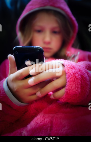 Ein junges Mädchen in einem rosa hoody Blick auf ein Apple iPhone Stockfoto