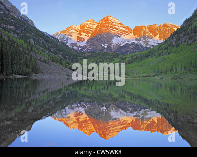 Schneebedeckte Gipfel, umgeben von bewaldeten Hänge reflektiert noch See Stockfoto