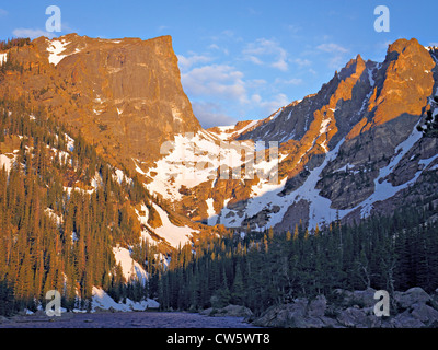 Granit Bergspitzen mit Schnee und Kiefern im unteren Pisten in orange Morgenlicht gesehen vom Ufer des Sees gebadet Stockfoto