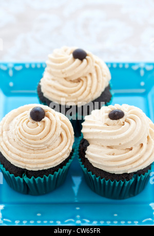 Schokoladentörtchen mit Buttercreme und Schokolade Espresso Kaffeebohnen auf Türkis Teller Stockfoto