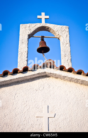 Bell und Kreuz auf einer weiß getünchten griechischen Kirche Stockfoto