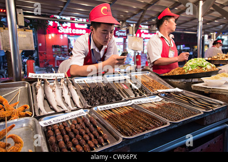 Straßenhändler verkaufen exotische Lebensmittel bei Nacht-Food Markt entlang der Wangfujing Street Einkaufsviertel in Peking, China Stockfoto