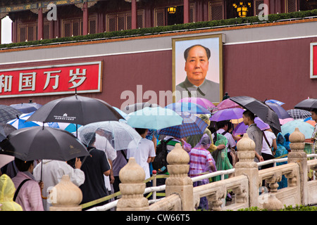 Touristen, die bergende unter Sonnenschirmen Stream in die Verbotene Stadt an einem regnerischen Sommertag in Peking, China Stockfoto