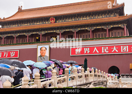 Touristen, die bergende unter Sonnenschirmen Stream in die Verbotene Stadt an einem regnerischen Sommertag in Peking, China Stockfoto