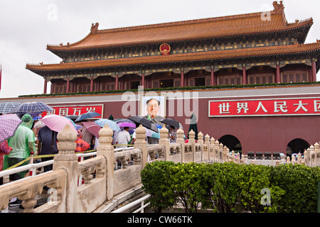 Touristen, die bergende unter Sonnenschirmen Stream in die Verbotene Stadt an einem regnerischen Sommertag in Peking, China Stockfoto