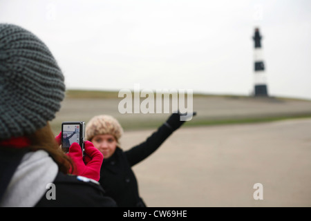 Frau unter Bild der jungen Frau, Leuchtturm im Hintergrund, Niederlande, Zeeland, Breskens, Sluis Stockfoto