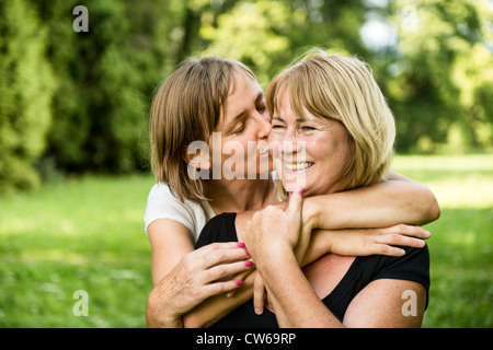 Erwachsene Tochter küssen ihre lächelnden glücklich senior Mutter - im Freien in der Natur Stockfoto