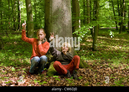 zwei Kinder sitzen mit geschlossenen Augen in einem Wald im Frühjahr, anhören von Vogelgezwitscher, zählen die verschiedenen Arten Stockfoto