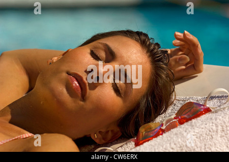 junge Frau vor einem Swimmingpool liegen Stockfoto