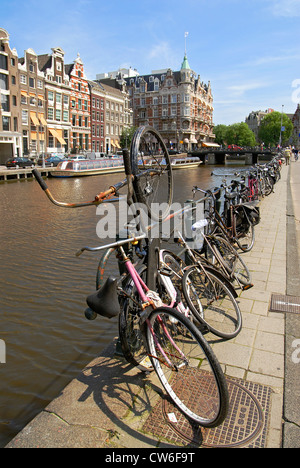 alte Fahrräder geparkt auf eine Gracht in der Innenstadt von Amsterdam, Niederlande Stockfoto