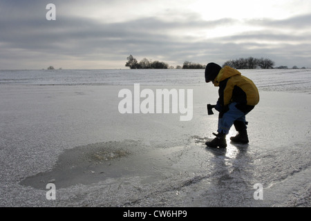 Strahlende Dorf Kind schlägt ein Loch in einem zugefrorenen See Stockfoto