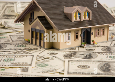 symbolisches Bild für Immobilien-Krise, Dollar-Banknoten und Modell eines Hauses, USA Stockfoto