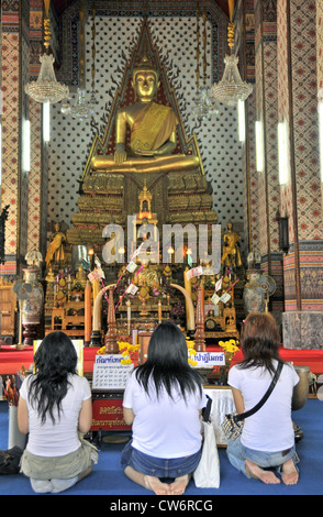 drei Frauen Jagd vor einer Buddha Statue, Thailand, Bangkok Stockfoto