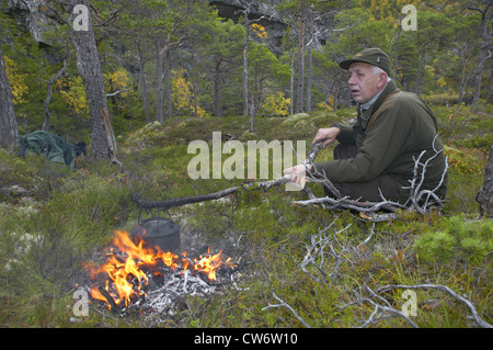 Elch, Europäischen Elch (Alces Alces Alces), Jäger, die Kaffeezubereitung über dem Lagerfeuer während einer Pause, Norwegen, Nord-Tröndelag, Flatanger Stockfoto