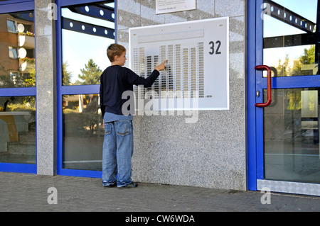 9 Jahre alter Junge am Türschild von einem mehrstöckigen Gebäude in Chorweiler, Deutschland, Nordrhein-Westfalen, Köln Stockfoto
