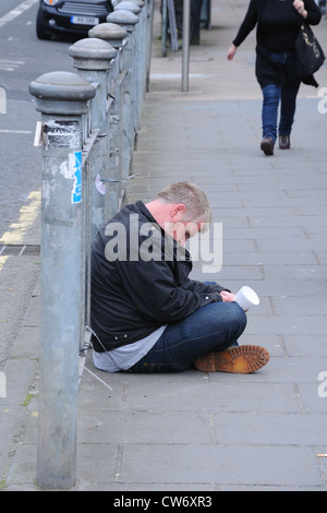 Mann um Geld betteln im Schlaf auf Pflaster im West End von Glasgow Stockfoto