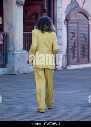 Ein Mann in einem gelben Anzug amüsiert sich auf dem Pier in Brighton. Stockfoto