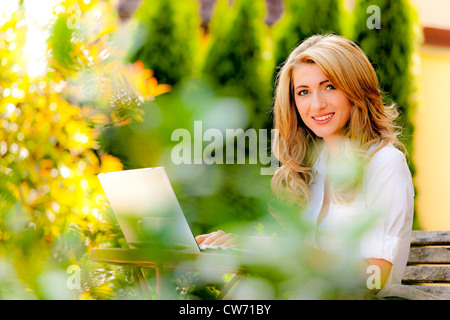 Frau mit Laptop im Garten Stockfoto