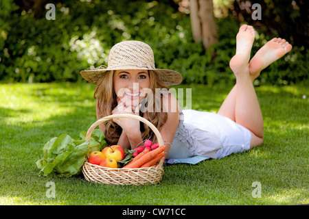 junge Frau in das Gras mit einem Obstkorb liegen Stockfoto