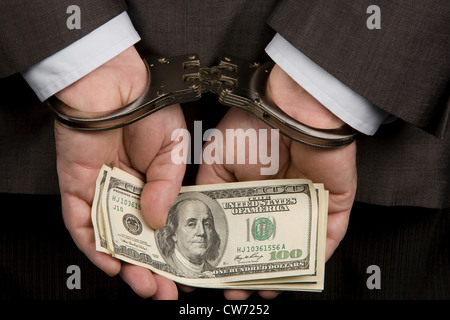 Mann mit Handschellen mit Dollar-Banknoten in den Händen, USA; Amerika Stockfoto