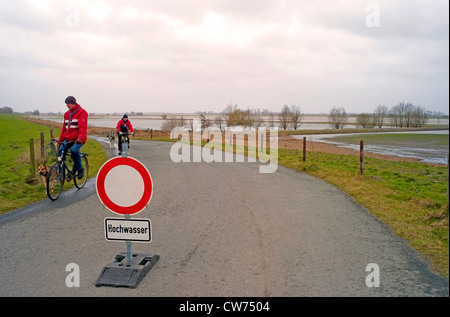 Verkehrsschild mit Hochwasser-Warnung und Durchgang nur für Residentsplaced in der Mitte eine asphaltierte Straße führt zu den Auen an der Weser in Neuenkirchen, Deutschland, Niedersachsen Stockfoto