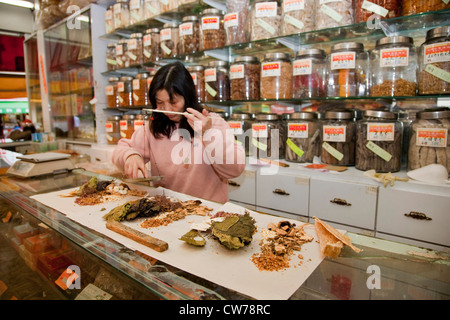 Frau mit einem Gewicht von Zutaten für traditionelle chinesische Medizin, Kanada, British Columbia, Vancouver Stockfoto