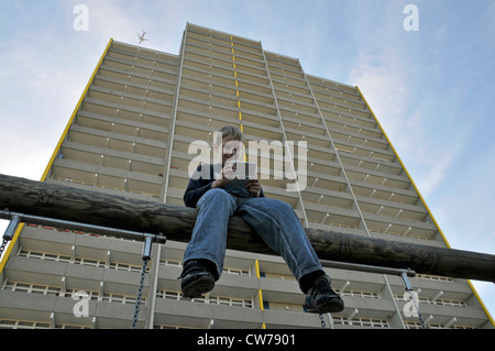 Jungen spielen mit Gameboy vor Hochhaus, Deutschland, Chorweiler, Köln Stockfoto