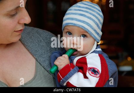 kleiner Junge mit gestreiften Mütze auf dem Arm halten Mutter Stockfoto