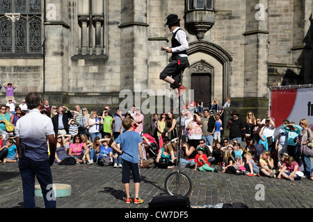 Zuschauer beim Edinburgh Festival Fringe auf dem West Parliament Square, Schottland, Großbritannien, beobachten einen Straßenkünstler auf einem Uni-Zyklus Stockfoto