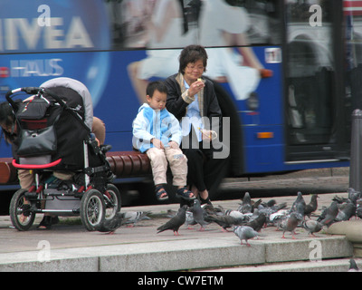 Kleiner Junge schaut Tauben Essen in der Innenstadt von Hamburg - Bus fährt in den Hintergrund, Deutschland, Hamburg Stockfoto