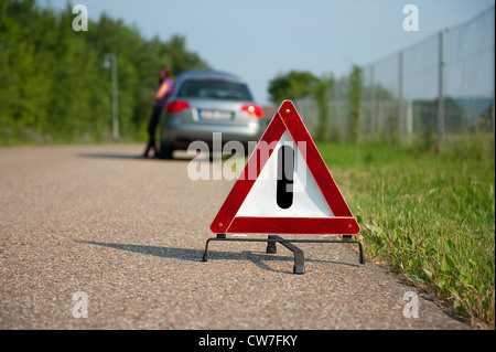 junges Mädchen mit einer Aufschlüsselung lehnt sich an ihrem Auto warten auf Hilfe Stockfoto