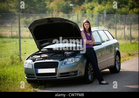 junges Mädchen mit einer Aufschlüsselung an ihr Auto gelehnt, mit offener Motorhaube warten auf Hilfe Stockfoto