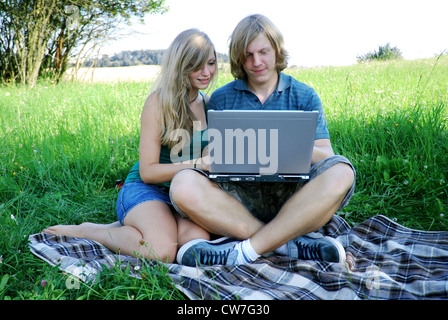 junges Paar in Liebe, sitzen auf einer Wiese mit laptop Stockfoto