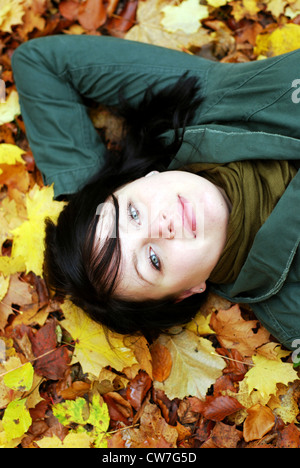 schöne Mädchen in Rückenlage, auf Herbstlaub liegend Stockfoto