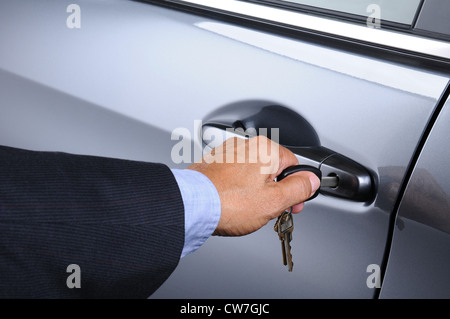 Nahaufnahme eines Mannes Hand einfügen einen Schlüssel in das Türschloss des Autos. Querformat. Auto und Mann sind nicht erkennbar. Stockfoto