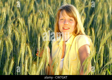Junge Frau sitzt in einem Getreidefeld Stockfoto