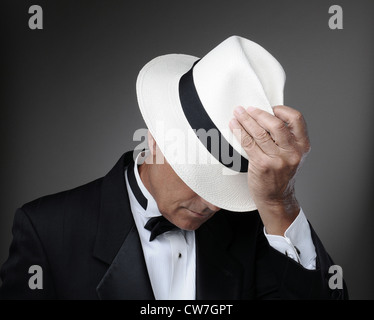 Nahaufnahme von einem nahen im Alter Mann trug einen Smoking und einen Panama-Hut. Horizontal über einem grauen Hintergrund. Stockfoto