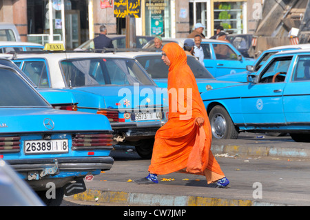 Frau in orange Kaftan am Taxistand, Marokko, Inezgane Stockfoto