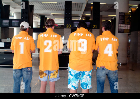 vier Touristen mit fortlaufend nummerierten T-shirts warten auf Gepäck am Flughafen, Spanien, Balearen, Mallorca Stockfoto