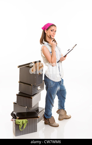 Lässig gekleidete Frau verfolgen von gepackten Sachen auf ihrem Brett, Stand in der Nähe einen Stapel von gestreiften Boxen, in die Kamera schaut. Stockfoto