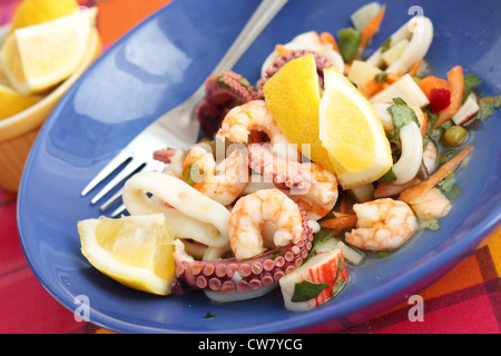 Meeresfrüchte-Salat mit Garnelen, Tintenfisch, Krabben-Sticks und Tintenfisch. In einem blauen Teller. Stockfoto