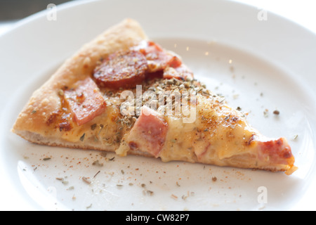 Pizza mit Wurst, Schinken, Hühnerfleisch, Paprika, Ananas auf einem weißen Teller. Stockfoto