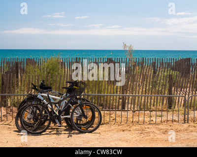 Eine Gruppe von Fahrrädern lehnt sich gegen einen Zaun am Meer Stockfoto