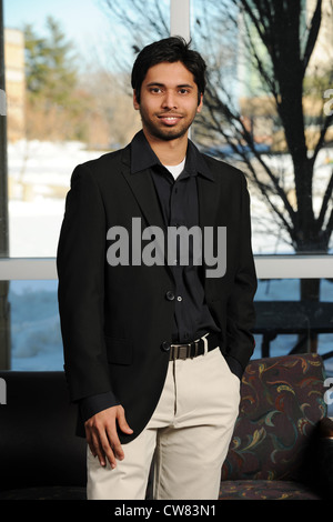 Junge indische Geschäftsmann aufstehen von einem Büro-Fenster Stockfoto