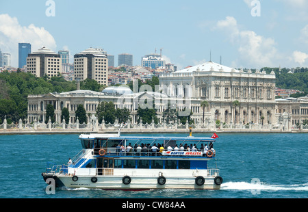 ISTANBUL, TÜRKEI. Ein Ausflugsschiff auf dem Bosporus mit den Dolmabahce Palast und die moderne Stadt hinter. 2012. Stockfoto