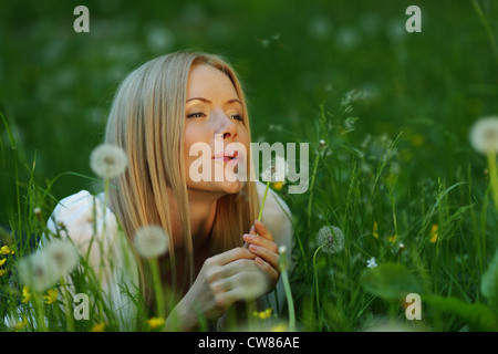 Mädchen bläst ein Löwenzahn auf der Wiese liegend Stockfoto