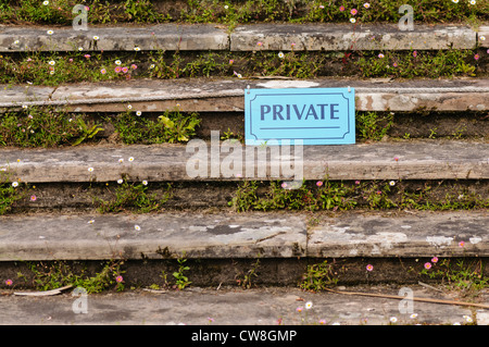 Schild mit der Aufschrift "privat" auf steinernen Stufen mit Blumen bedeckt Stockfoto