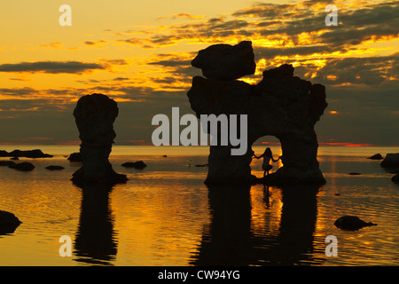 Mädchen posiert in einem Rauk. Rauk ist das lokale Wort für diese Seastacks (erodierte Kalkstein-Formationen). Langhammar, Fårö, Gotland. Stockfoto