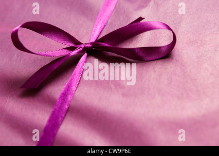 Ein Geschenk, verpackt in lila Seidenpapier und Satinschleife Stockfoto